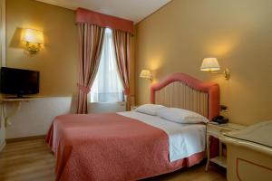 um quarto de hotel com uma cama com um cobertor vermelho e uma janela em Casa Burchielle em Veneza