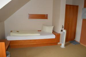 a small bedroom with a bed with white sheets at Hotel Daimerwirt in Moosinning