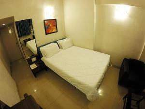 um pequeno quarto com uma cama com lençóis brancos em Tex Palazzo Hotel em Surat