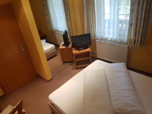 LitzendorfにあるGasthof Krappのベッド1台とテレビが備わる小さな客室です。