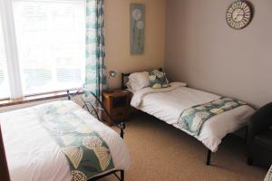a bedroom with two beds and a window with a clock at The Mayhill Hotel in Monmouth