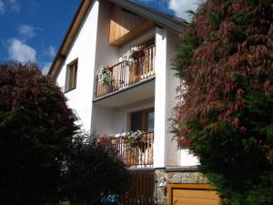 ein weißes Haus mit Balkonen und Blumen darauf in der Unterkunft Apartman Aneta in Skalná