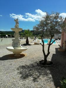 a fountain in the middle of a courtyard with a tree at Les Gites de Kevinou in Vallon-Pont-dʼArc