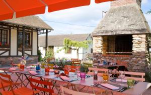 a patio with tables and chairs and a stone fireplace at Les Canisses in Saint-Pierre-la-Garenne