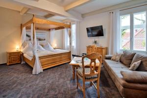 ein Schlafzimmer mit einem Himmelbett und einem Sofa in der Unterkunft Hotel Packhaus in Hooksiel