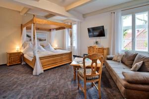 a bedroom with a canopy bed and a couch at Hotel Packhaus in Hooksiel