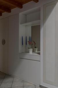 una cocina con armarios blancos con asas azules y espejo en Il Soppalco, en Luino