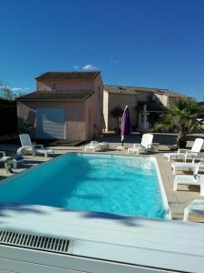 a swimming pool with white chairs and a house at Les Gites de Kevinou in Vallon-Pont-dʼArc +21 photos