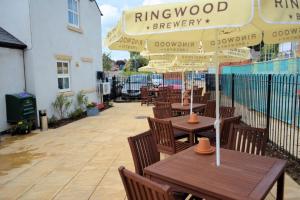 a patio with tables and chairs with umbrellas at The Swan @Old Stratford in Milton Keynes