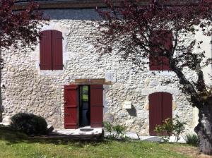 SosにあるLe Petite Grange Giteの赤いドアと窓のある石造りの建物