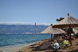 a group of people sitting on a beach with umbrellas at Holiday S&M in Lopar