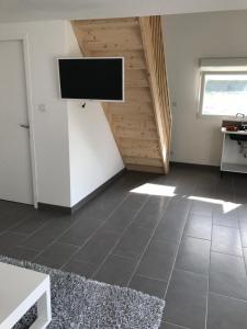 ein Wohnzimmer mit einem Flachbild-TV an der Wand in der Unterkunft Petite maison indépendante in Bulgnéville