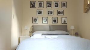 a bedroom with a white bed with pictures on the wall at Dépendance La Casetta in Castellammare di Stabia