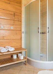 a bathroom with a shower and towels on a wooden wall at Domki u Kromki in Kacwin