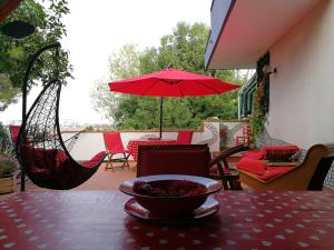 una mesa con un bol de fruta y una sombrilla roja en The Incantation Guest House, en Montesilvano