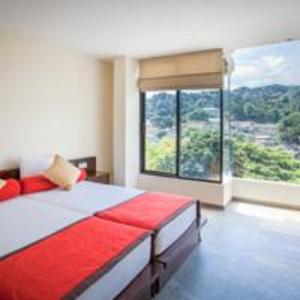 een slaapkamer met een bed en een groot raam bij Oak Ray City Hotel in Kandy