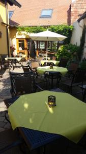 eine Außenterrasse mit Tischen, Stühlen und einem Sonnenschirm in der Unterkunft Ellenbergs Restaurant & Hotel in Heßheim