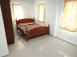a wooden bed in a room with two windows at Harum Manis Country House in Kangar