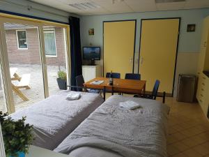 two beds in a room with a table and a dining room at Guest House Ons Hoekje in Houten
