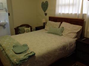 a bedroom with a bed with two green towels on it at 77 ON 7th Street in Hermanus
