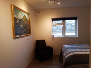 um quarto com um quadro e uma cadeira ao lado de uma cama em Bólstaðarhlíð Guesthouse em Bólstaðarhlíð