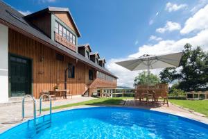 una piscina di fronte a una casa con ombrellone di Wellness Hotel Florián České Žleby a Stožec