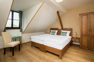 a bedroom with a bed and a chair at Wellness Hotel Florián České Žleby in Stožec