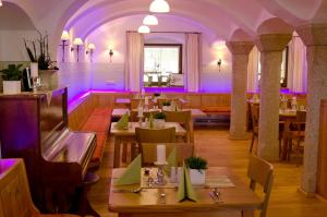 a restaurant with tables and chairs and purple lighting at Hotel Gasthof zur Post in Bärnau