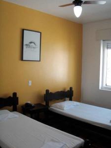a bedroom with two beds and a window and a fan at Farol Hotel in Torres