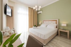 a bedroom with a large white bed and a television at Castello Boutique Rooms in Kavála
