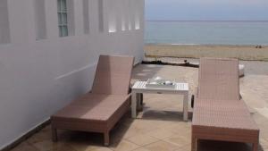 two chairs and a table on a patio with the beach at Marine House Andrianna -Adults only in Siviri