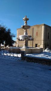 a fountain in the snow in front of a building at Piazza Castello in Santo Stefano Quisquina