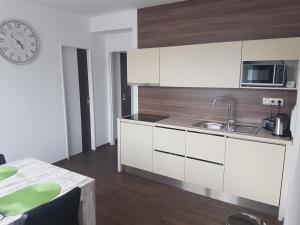 a kitchen with white cabinets and a sink and a table at Apartmány u skanzenu in Rožnov pod Radhoštěm