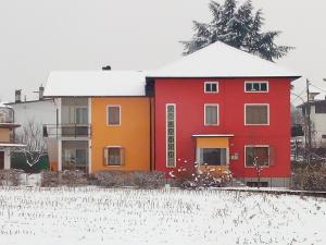 une maison rouge et orange dans la neige dans l'établissement B&B Colli's Dolomites, à Belluno