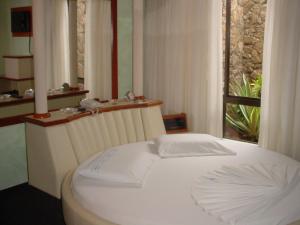 a white bed in a room with a window at Hotel Paradise in Ijuí