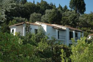 biały dom na wzgórzu z drzewami w obiekcie Studios Andreas w mieście Boukari