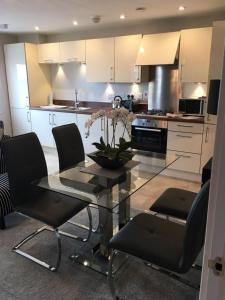 a kitchen with a glass table and black chairs at Cardiff luxury apartments in Cardiff