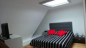 a bedroom with a black and white bed with red pillows at Residence le Crisenoy in Houlgate