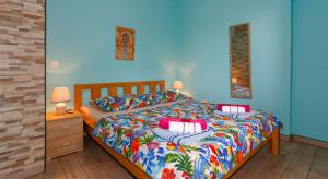 a blue bedroom with a bed with colorful sheets and pillows at Stonehouse with swimming pool Villa Anita in Okrug Donji +46 photos