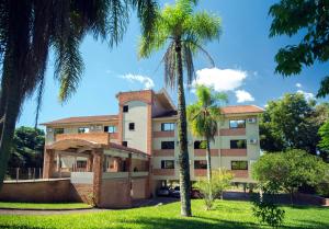 a building with palm trees in front of it at Hotel Jardim Europa in Ijuí