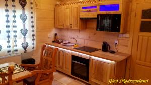 a kitchen with wooden cabinets and a sink and a table at Pod Modrzewiami in Ciche +25 photos