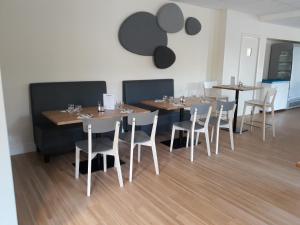 uma sala de jantar com mesas de madeira e cadeiras brancas em La Godinière em Cholet