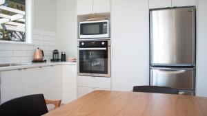 a kitchen with a table and a microwave and a refrigerator at Rotorua beauty in Rotorua