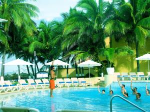 a man standing in the swimming pool at a resort at Aca Suites Ixtapa in Ixtapa