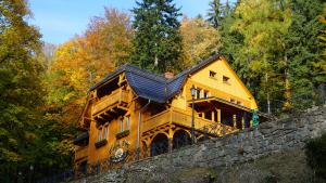 a large yellow house on top of a stone wall at Pensjonat Alpejski Dwór in Miedzygorze
