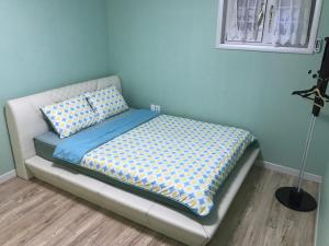 een bed in een kamer met een blauwe muur bij Namhae Frankfurt Pension in Namhae