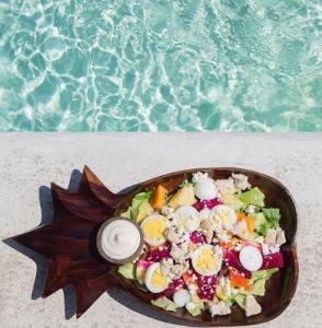 a bowl of salad on a table next to the water at Gravity Eco Boutique Hotel - Adults Only in Uluwatu