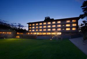 un grand bâtiment la nuit avec une pelouse devant lui dans l'établissement Toba International Hotel Shiojitei, à Toba