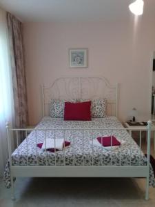 1 dormitorio con 1 cama blanca y 2 almohadas rojas en Sandanski Peak Guest Rooms en Sandanski