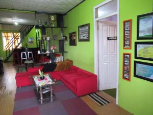 a living room with a red couch and green walls at Green Savannah Homestay Syariah in Diyeng